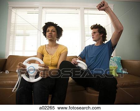Stock Photography - USA, Utah, Provo, young couple playing video games in living room. Fotosearch