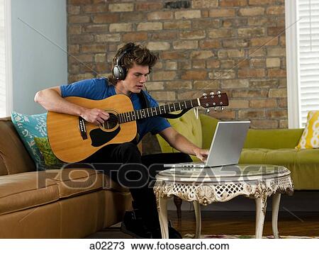 USA, Utah, Provo, young man playing guitar, using laptop in living room View Large Photo Image Stock Image - USA, Utah, Provo, young man playing guitar, using laptop in living room. Fotosearch