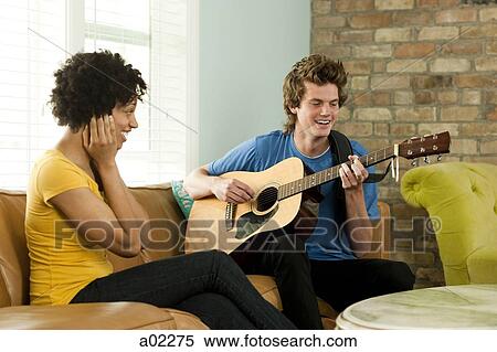 USA, Utah, Provo, young man playing guitar with young woman covering ears View Large Photo Image Stock Photography - USA, Utah, Provo, young man playing guitar with young woman covering ears. Fotosearch