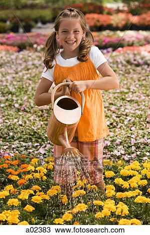 Stock Image - USA, Utah, Salem, portrait of girl (8-9) watering flowers. Fotosearch