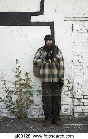 Stock Photo - USA, Utah, Salt Lake City, Homeless man standing in front of brick wall. Fotosearch