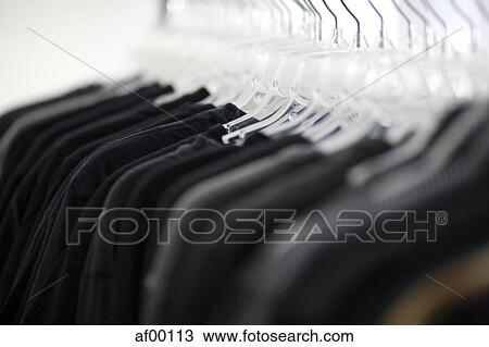 Stock Image - USA, Utah, Salt Lake City, Suits hanging on rail. Fotosearch