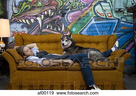 USA, Utah, Salt Lake City, Young man sleeping on sofa with dog, graffiti in background View Large Photo Image Stock Photo - USA, Utah, Salt Lake City, Young man sleeping on sofa with dog, graffiti in background. Fotosearch