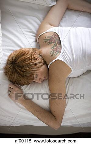 Stock Photography - USA, Utah, Salt Lake City, Young woman sleeping on bed, elevated view. Fotosearch