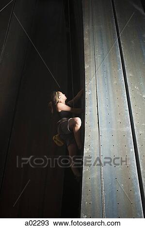 Stock Image - USA, Utah, Sandy, teenage girl (14-15) on indoor climbing wall. Fotosearch