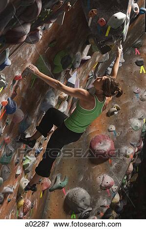 Stock Photo - USA, Utah, Sandy, young woman on indoor climbing wall. Fotosearch