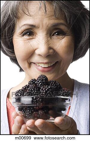 Stock Photo - woman holding up a bowl of blackberries. Fotosearch