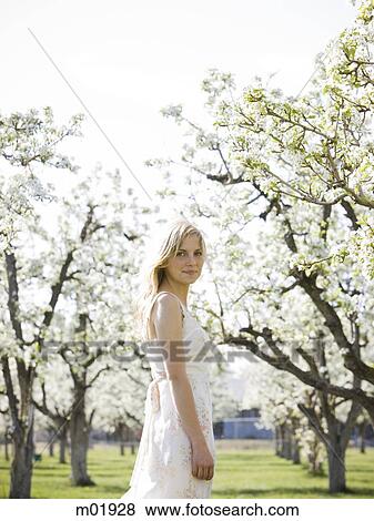 Stock Photo - woman in a blossoming orchard. Fotosearch