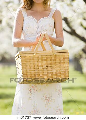 Stock Photo - woman in a white dress holding a picnic basket. Fotosearch