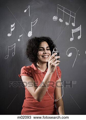 Stock Image - woman listening to mp3 player. Fotosearch
