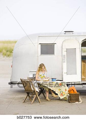 woman sitting at a table on the beach outside her airstream classic trailer View Large Photo Image Stock Image - woman sitting at a table on the beach outside her airstream classic trailer. Fotosearch