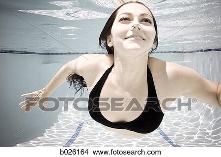 Picture - woman swimming underwater in a pool. Fotosearch