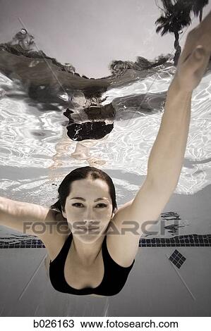 Stock Image - woman swimming underwater in a pool. Fotosearch