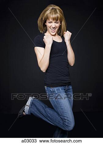 Stock Image - Young cheerful woman jumping, studio shot. Fotosearch