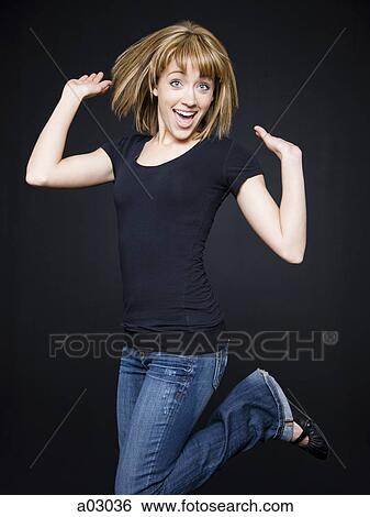 Stock Photograph - Young cheerful woman jumping, studio shot. Fotosearch