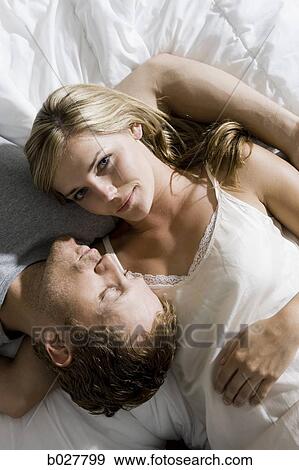 Stock Photo - young couple lying on the bed. Fotosearch