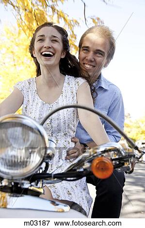 Stock Photo - Young couple riding on motorcycle in autumn forest. Fotosearch