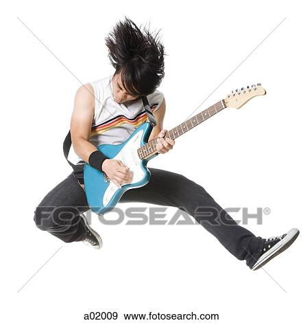 Stock Photo - Young man jumping and playing guitar, studio shot. Fotosearch