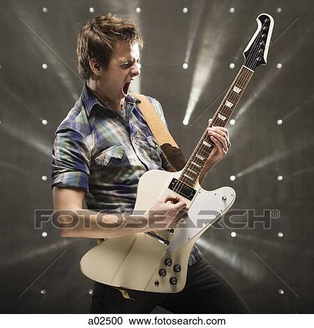 Young man playing bass guitar, studio shot View Large Photo Image Stock Image - Young man playing bass guitar, studio shot. Fotosearch