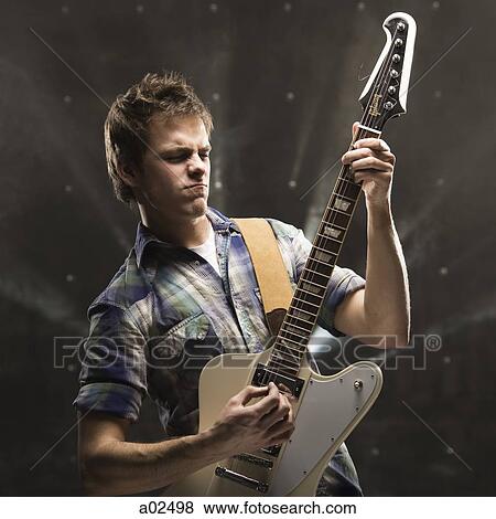 Young man playing bass guitar, studio shot View Large Photo Image Stock Photo - Young man playing bass guitar, studio shot. Fotosearch