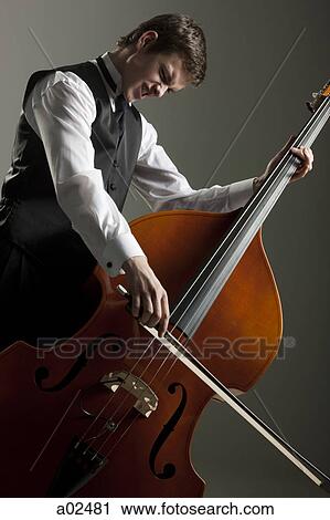 Young man playing double bass, studio shot View Large Photo Image Stock Image - Young man playing double bass, studio shot. Fotosearch