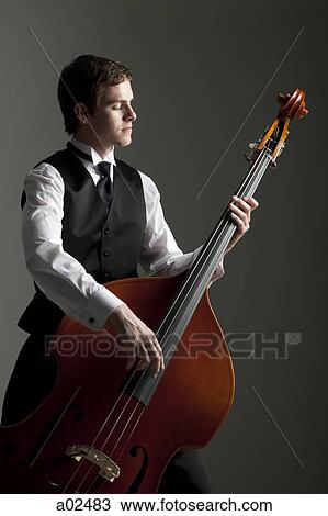 Young man playing double bass, studio shot View Large Photo Image Stock Image - Young man playing double bass, studio shot. Fotosearch