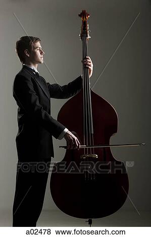 Young man playing double bass, studio shot View Large Photo Image Stock Photo - Young man playing double bass, studio shot. Fotosearch