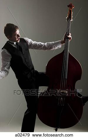 Young man playing double bass, studio shot View Large Photo Image Stock Photo - Young man playing double bass, studio shot. Fotosearch