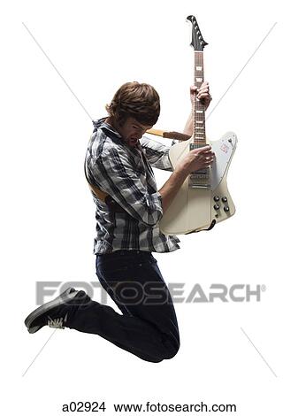 Picture - Young man playing electric guitar and jumping. Fotosearch