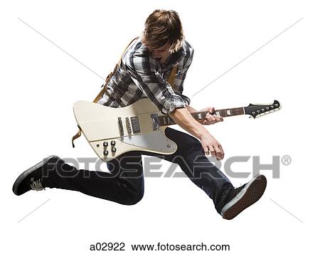 Stock Image - Young man playing electric guitar and jumping. Fotosearch