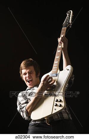 Young man playing electric guitar, studio shot View Large Photo Image Picture - Young man playing electric guitar, studio shot. Fotosearch