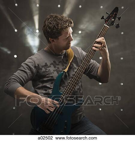 Stock Image - Young man playing electric guitar, studio shot. Fotosearch