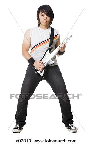 Young man playing electric guitar video game, studio shot View Large Photo Image Stock Image - Young man playing electric guitar video game, studio shot. Fotosearch