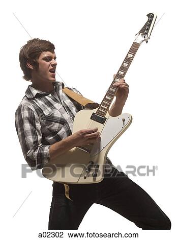 Stock Image - Young man playing guitar, studio shot. Fotosearch
