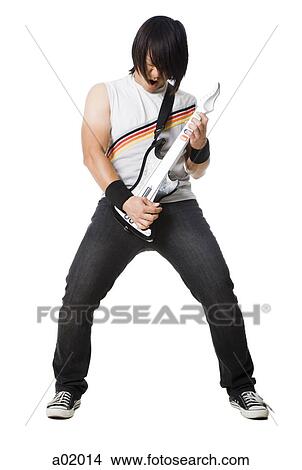 Picture - Young man playing guitar video game and screaming, studio shot. Fotosearch