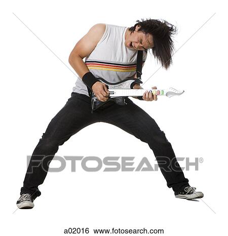 Stock Photograph - Young man playing guitar video game and singing, studio shot. Fotosearch