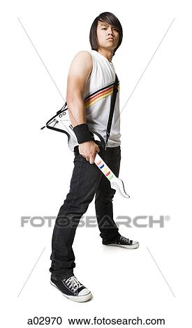 Stock Image - Young man playing guitar video game, portrait. Fotosearch