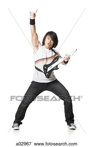 Stock Photo - Young man playing guitar video game, portrait. Fotosearch