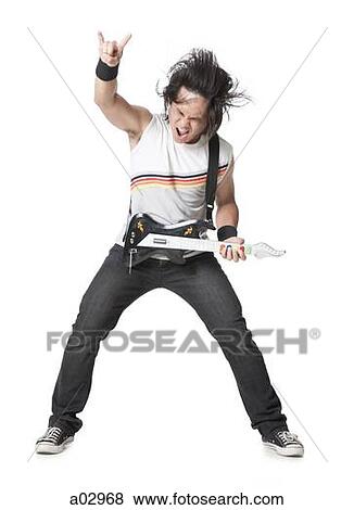 Stock Photo - Young man playing guitar video game, portrait. Fotosearch