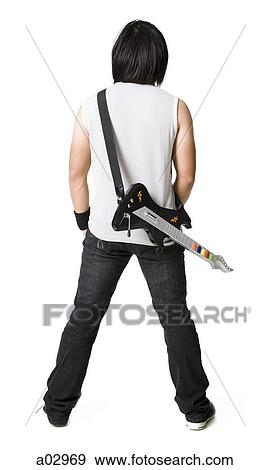 Stock Photo - Young man playing guitar video game, portrait. Fotosearch