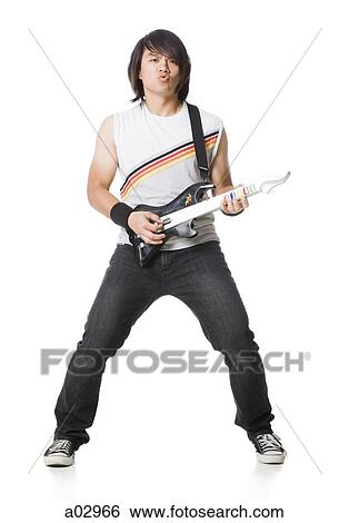 Stock Photograph - Young man playing guitar video game, portrait. Fotosearch