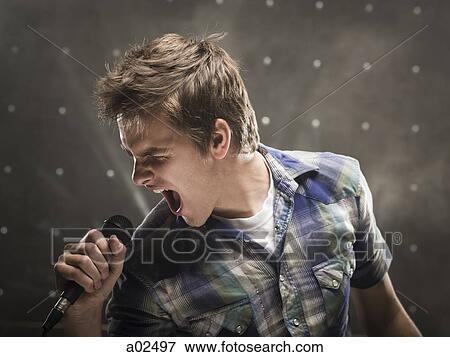 Young man singing, studio shot View Large Photo Image Stock Photo - Young man singing, studio shot. Fotosearch
