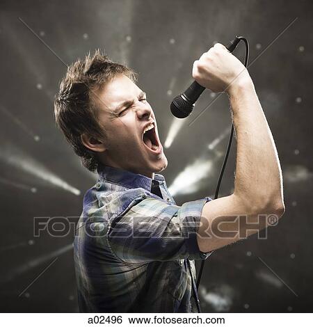 Stock Photograph - Young man singing, studio shot. Fotosearch