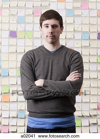 Young man standing in front of wall covered with adhesive notes, portrait View Large Photo Image Stock Image - Young man standing in front of wall covered with adhesive notes, portrait. Fotosearch