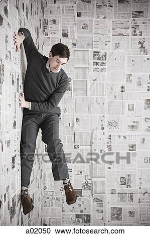 Young man stuck to wall covered with newspapers, studio shot View Large Photo Image Stock Image - Young man stuck to wall covered with newspapers, studio shot. Fotosearch