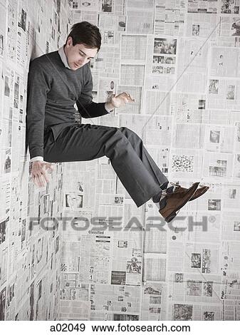 Young man stuck to wall covered with newspapers, studio shot View Large Photo Image Stock Photo - Young man stuck to wall covered with newspapers, studio shot. Fotosearch