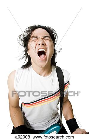 Stock Photo - Young man with guitar shouting, studio shot, portrait. Fotosearch