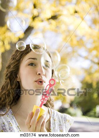 Picture - Young woman blowing soap bubbles in Autumn forest. Fotosearch