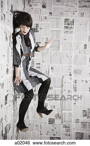 Young woman falling down a wall covered with newspapers, studio shot View Large Photo Image Stock Photograph - Young woman falling down a wall covered with newspapers, studio shot. Fotosearch