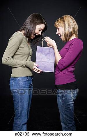 Young woman giving friend gift bag, studio shot View Large Photo Image Stock Image - Young woman giving friend gift bag, studio shot. Fotosearch